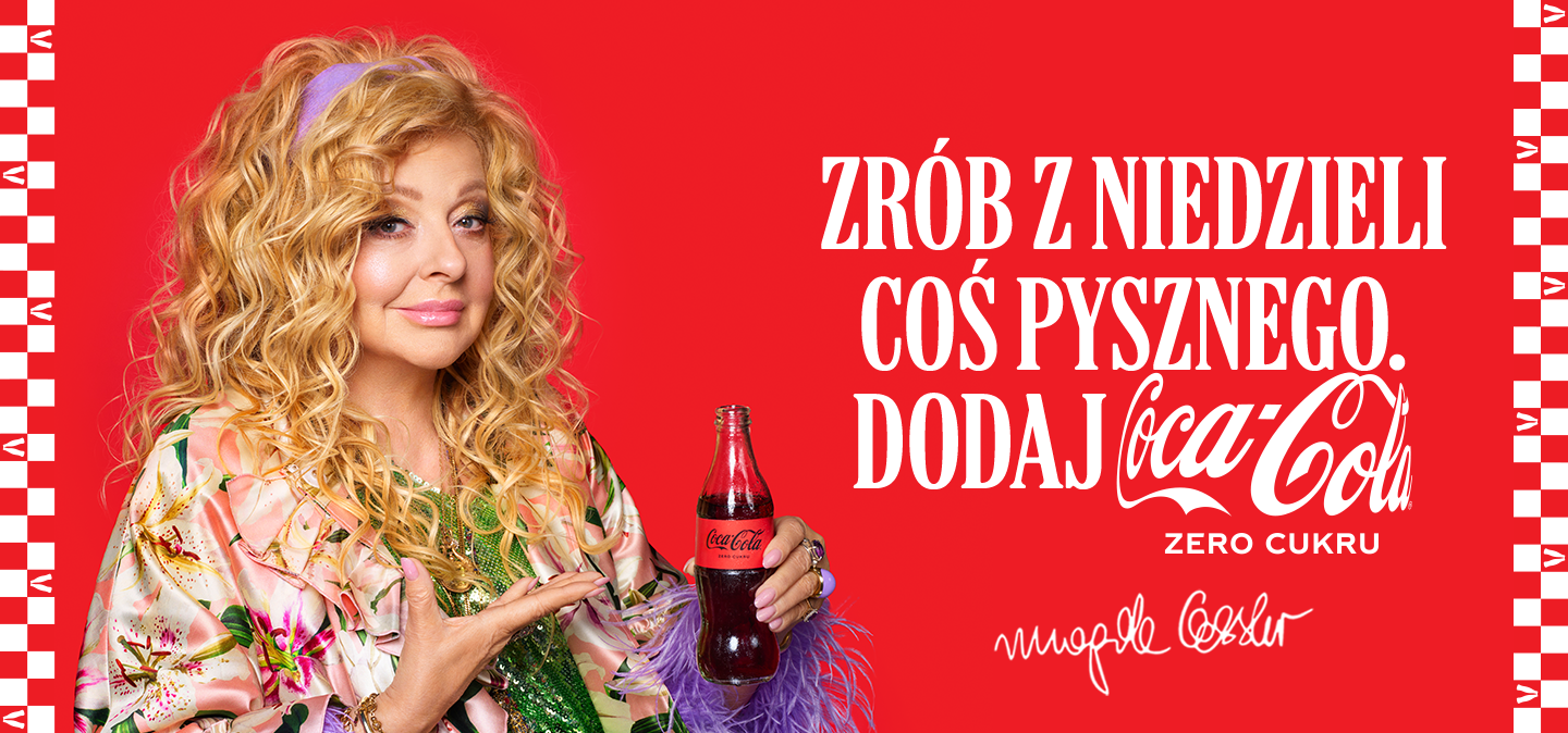 Magda Gessler trzymająca butelkę Coca-Cola na czerwonym tle.