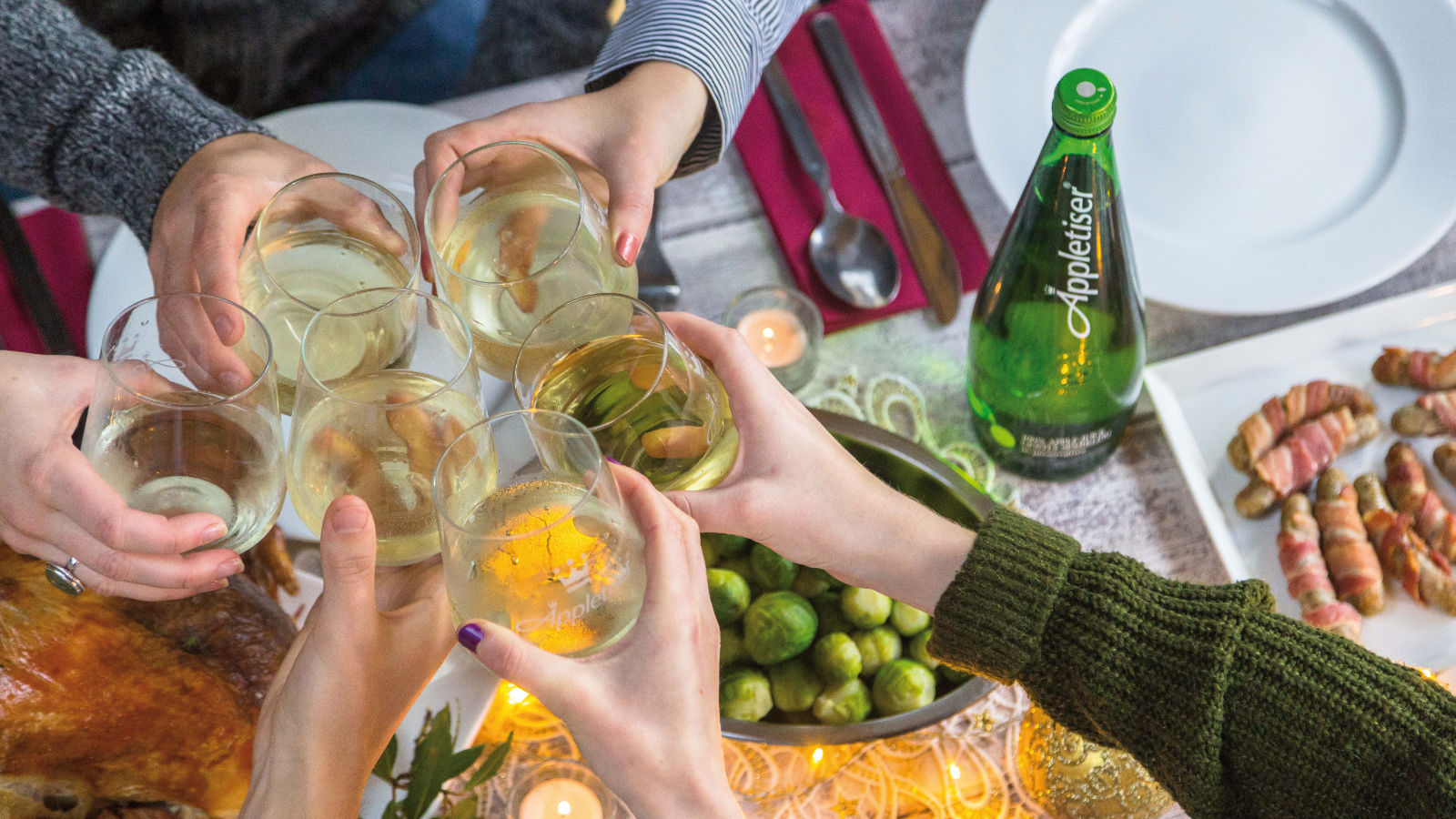 Um grupo de pessoas realiza um brinde com copos com Appletiser durante um piquenique