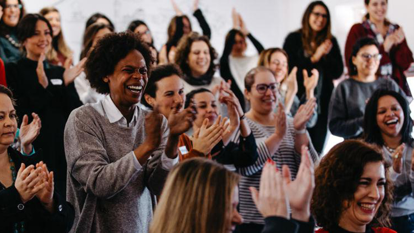 Grupo de mulheres de pé batendo palmas