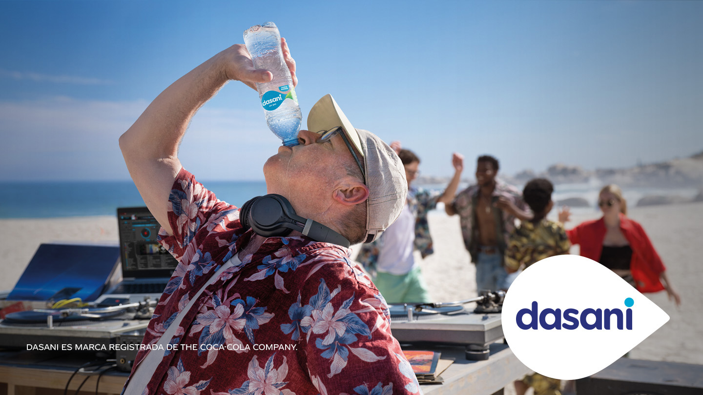 Hombre toma de una botella de Dasani en una playa
