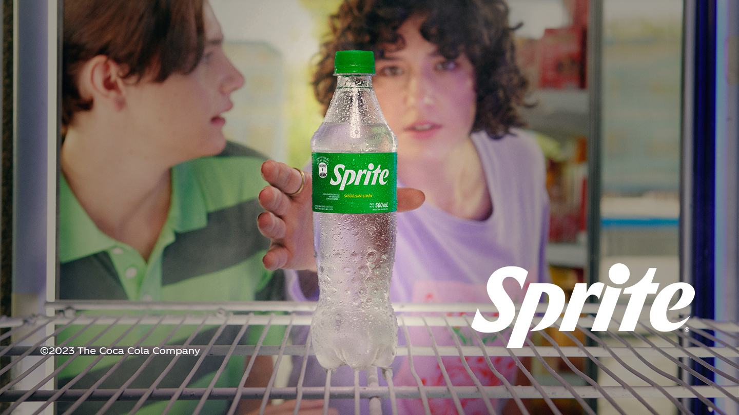 Dos jóvenes agarran una botella de Sprite de una heladera