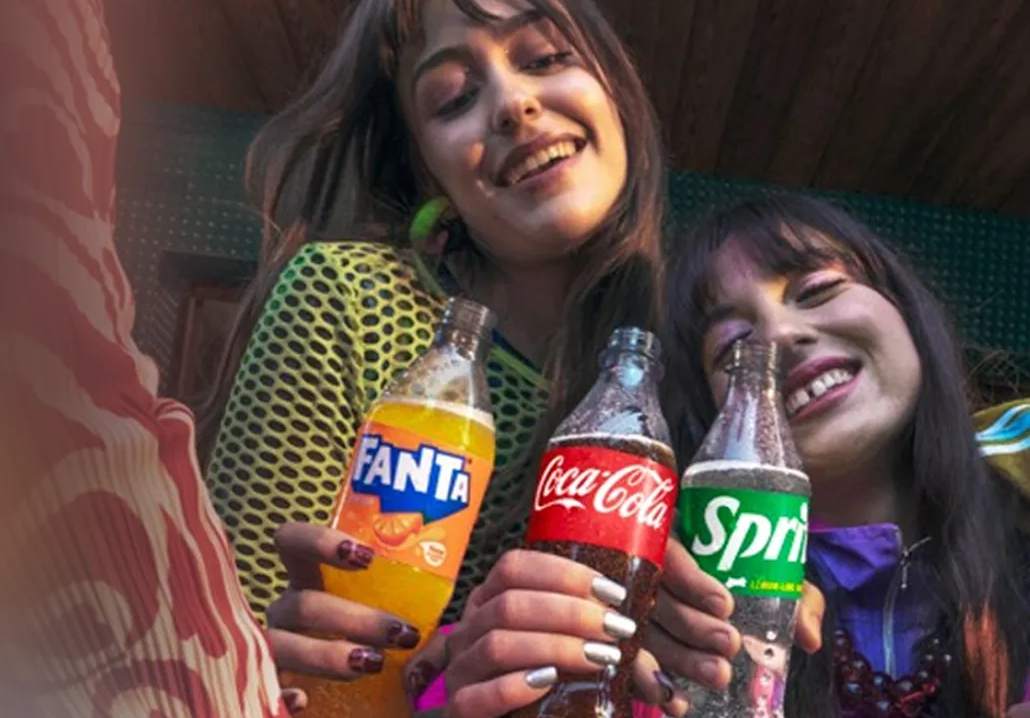 Mai multe persoane ciocnesc doze de Fanta, Coca‑Cola și Sprite.