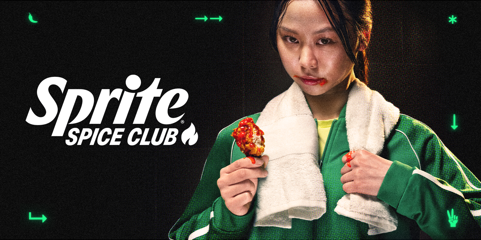 O tanara imbracata intr-un echipament verde, cu un prosop in jurul gatului, mancand aripioare picante