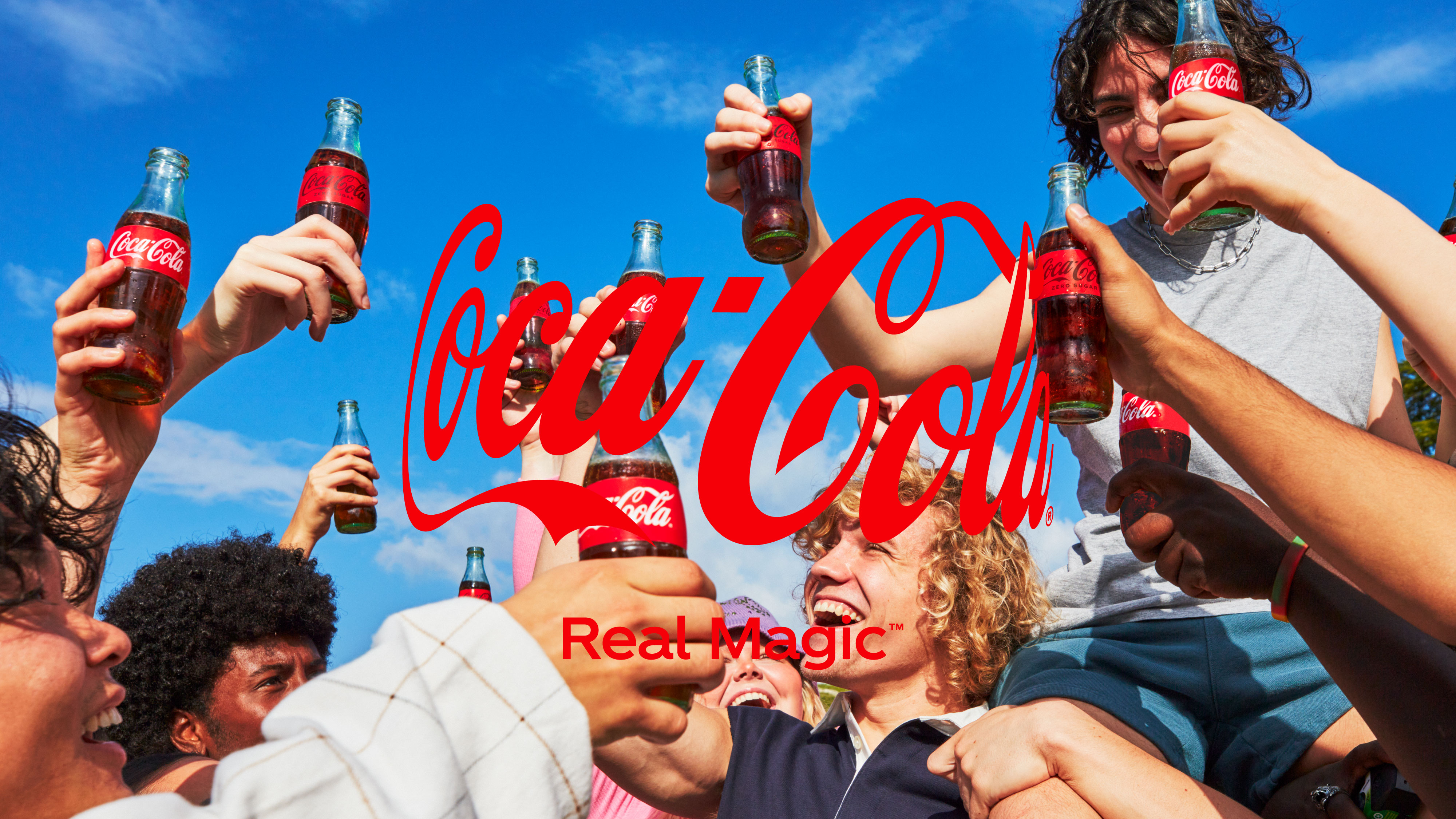 Un bărbat tânăr, cu barbă, ține o chitară și bea Coca-Cola dintr-o sticlă