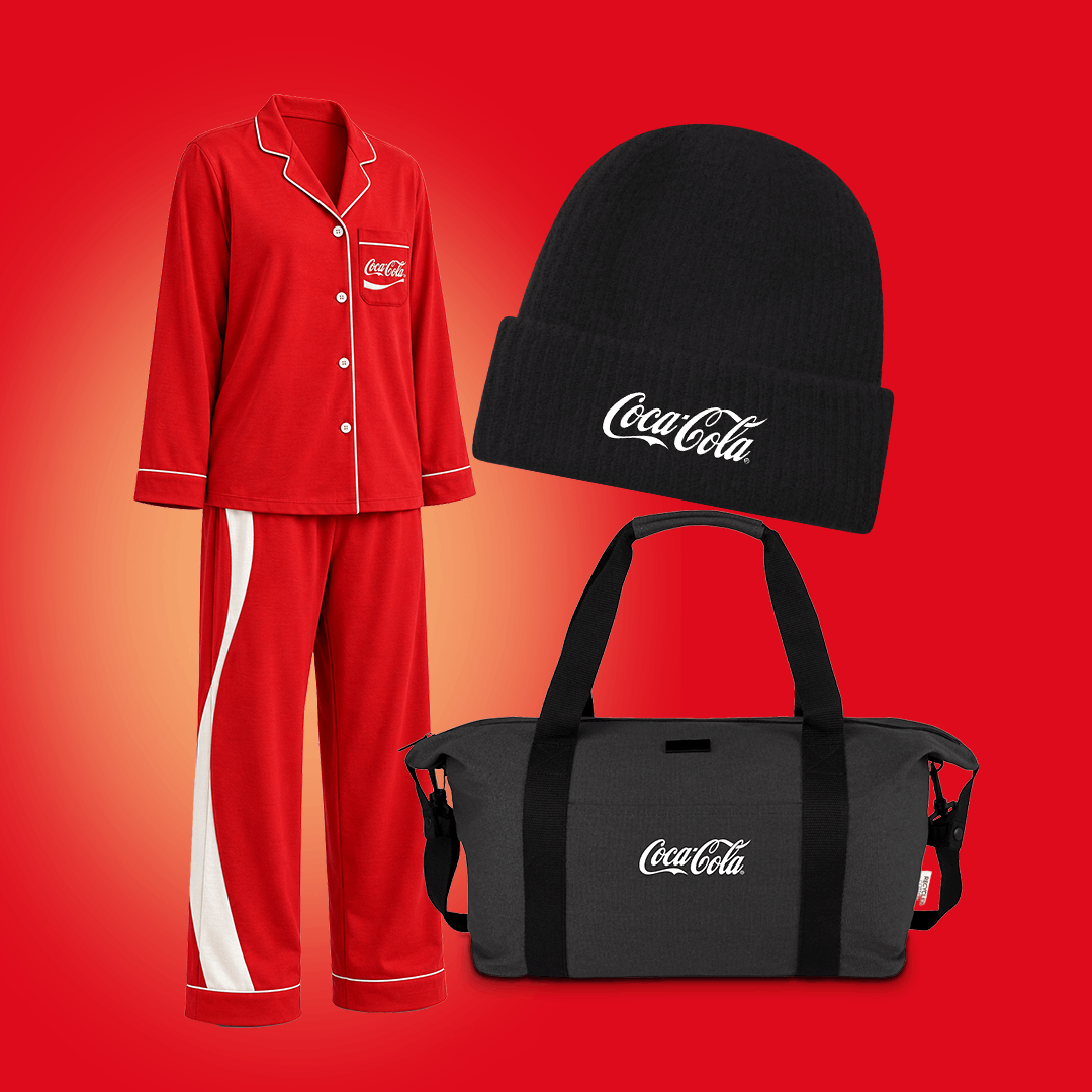 Ett rött Coca-Cola-pyjasset med vita detaljer visas tillsammans med en svart mössa och en svart väska med Coca-Cola-logotyp mot en röd bakgrund.