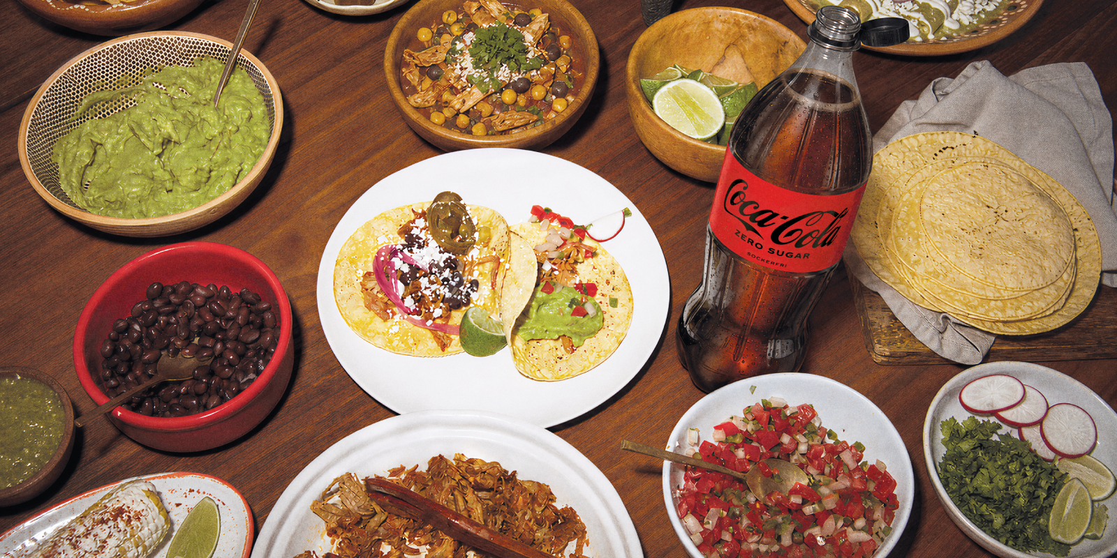 Olika skålar med taco-tillbehör och en Coca-Cola Zero-flaska