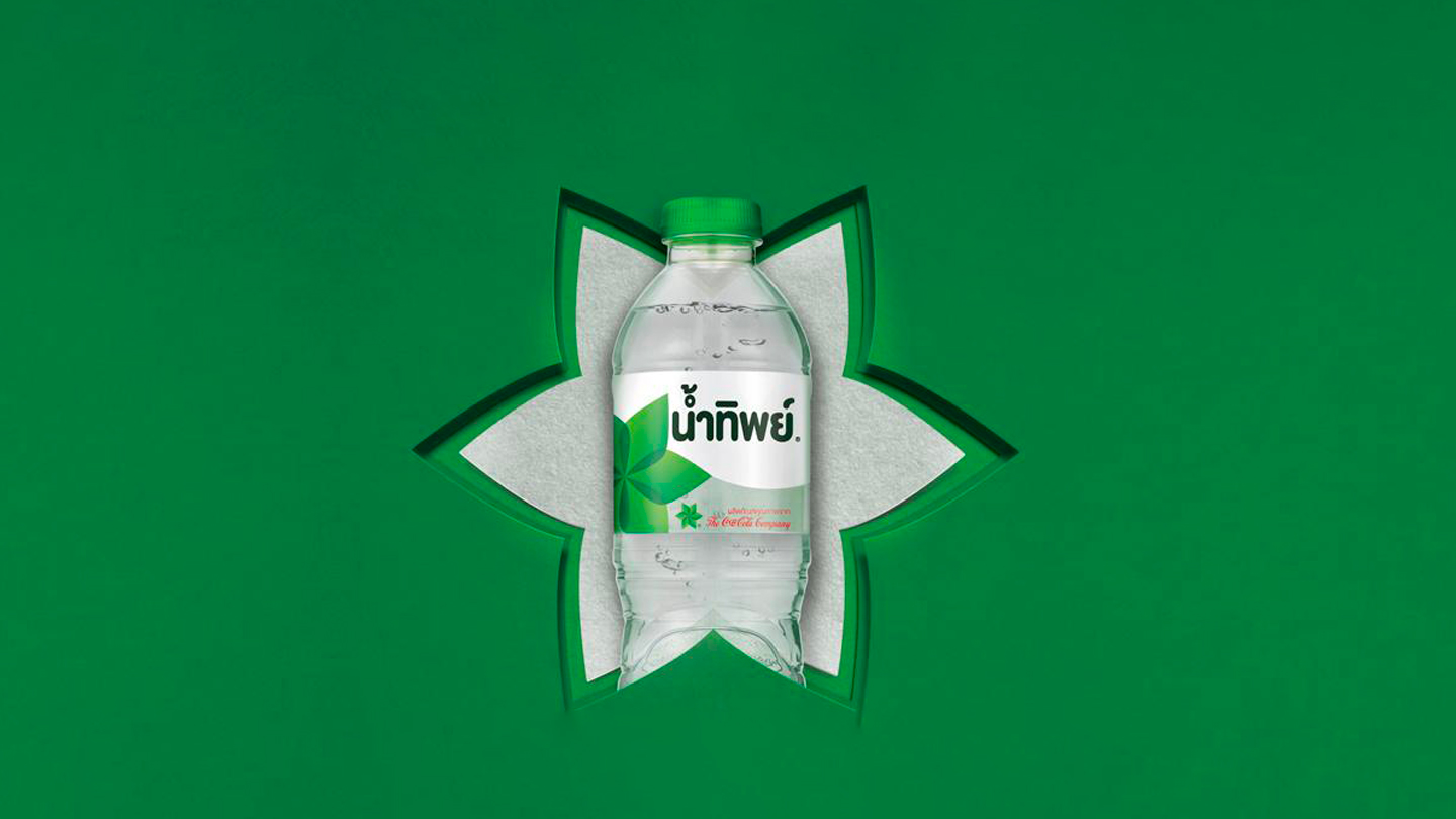 น้ำทิพย์ดื่มน้ำในขวดพลาสติกบนพื้นสีเขียว