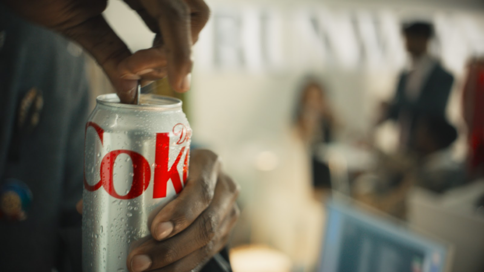 A close-up of a hand holding a chilled Diet Coke