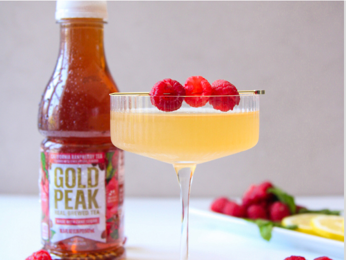 gold peak bottle next to orange mocktail with raspberries