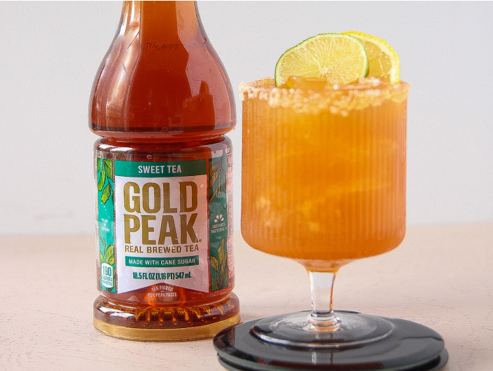 gold peak bottle next to orange mocktail with lime