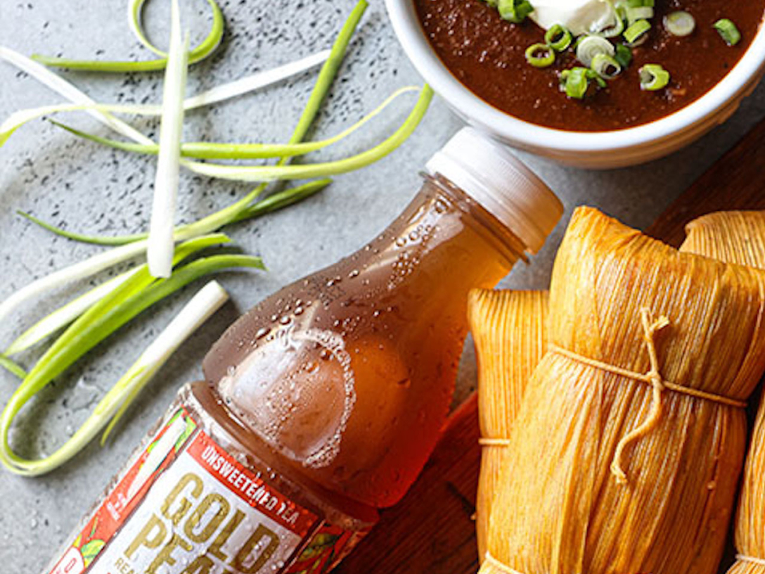 a bottle of gold peak tea next to tamales and green onions