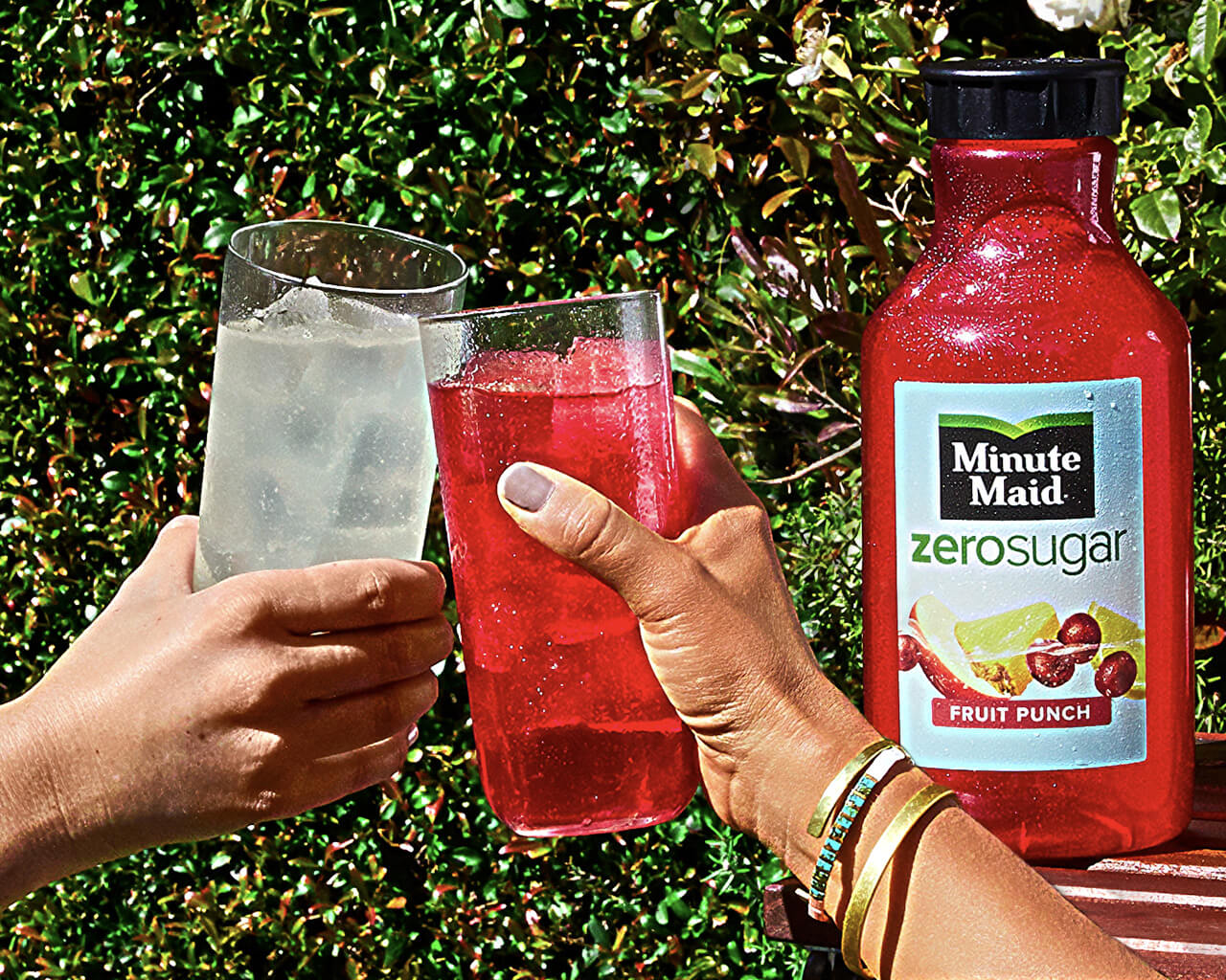 Two glasses toasting with a bottle of minute Maid Zero Sugar
