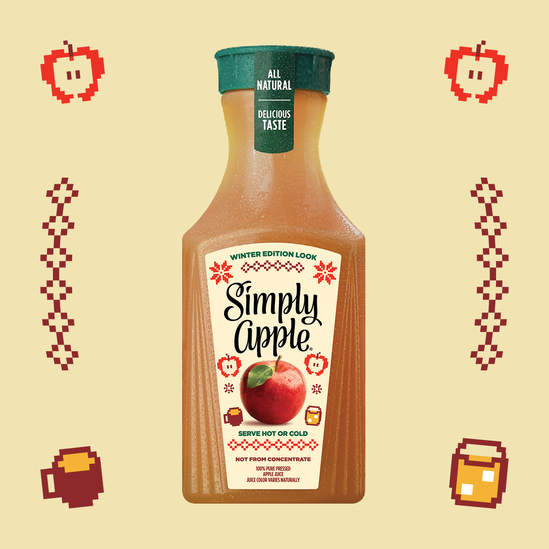 A bottle of Simply Apple juice with a green cap marked "All Natural, Delicious Taste" and a cream-coloured "Winter Edition Look" label. The label shows a red apple, red snowflakes and the words "Serve Hot or Cold" and "Not From Concentrate," and the bottle sits on a pale yellow background with pixel-style apples, mugs and red diamond patterns around it.