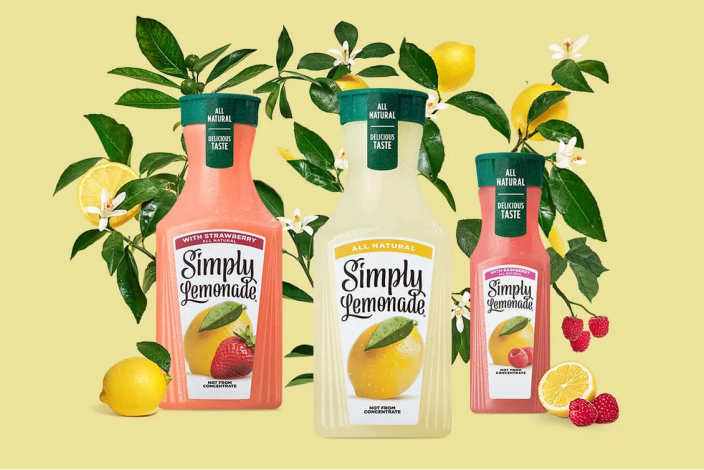 Three containers of different Simply Lemonade flavors with fruit and greenery in the background