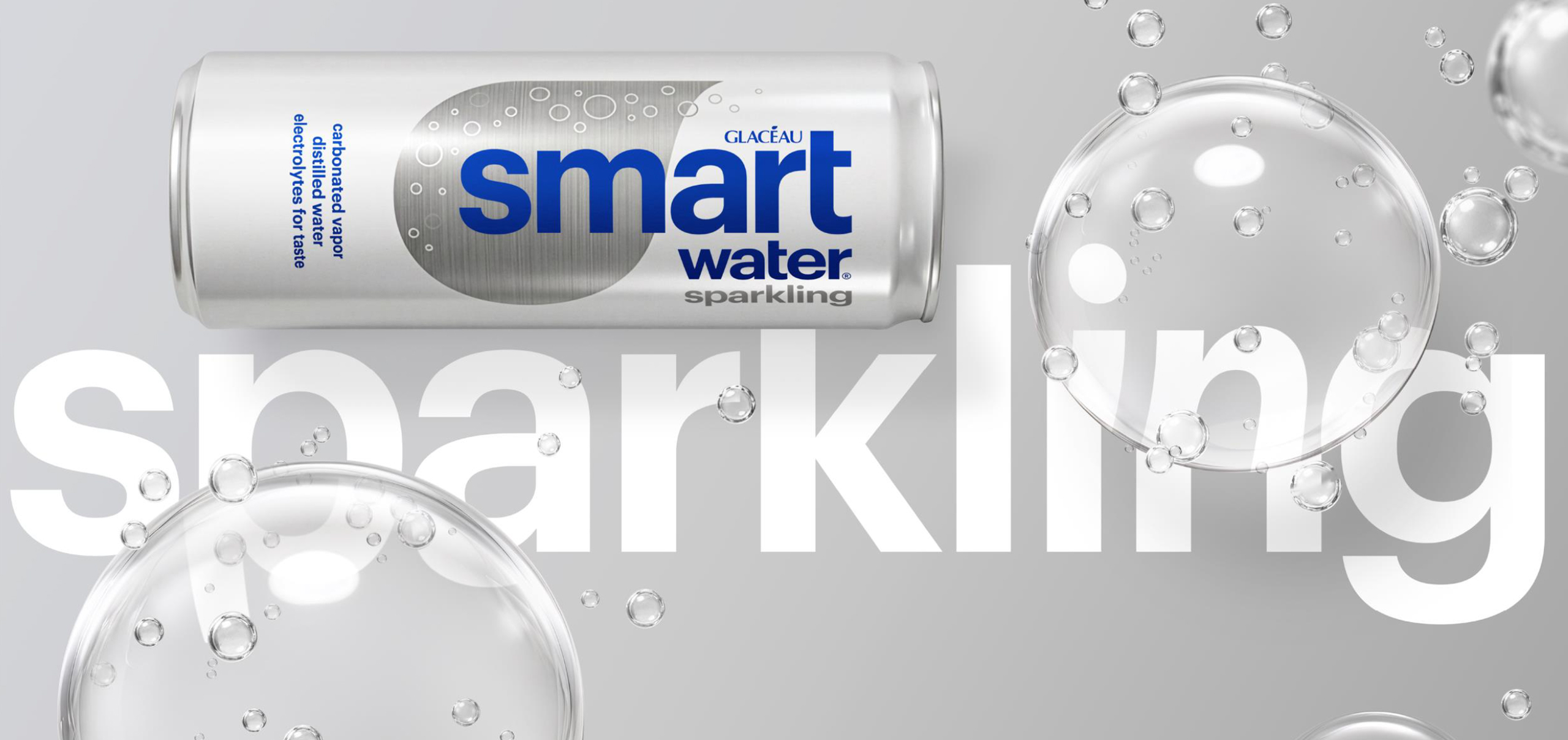 A silver Glacéau Smartwater Sparkling can lying on its side, labeled "carbonated vapor distilled water electrolytes for taste," set against a gray background with large translucent bubbles and the word "sparkling" in bold white text.