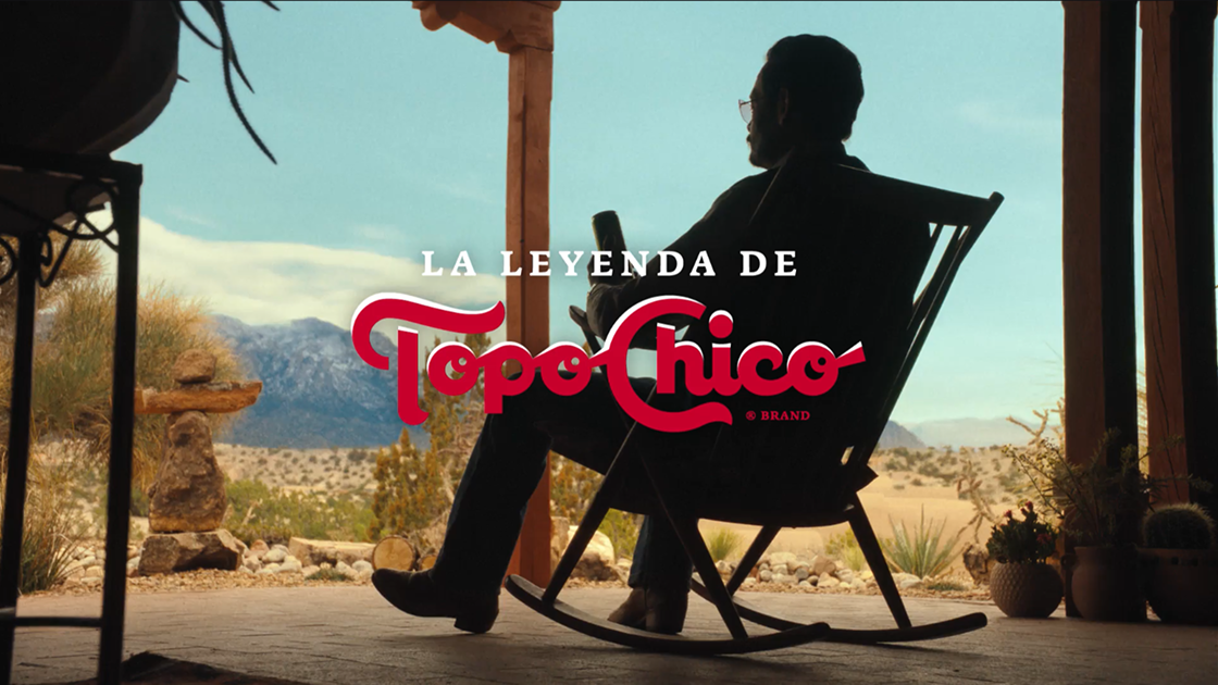 a silhouette of a man sitting in a rocking chair on a porch in the desert