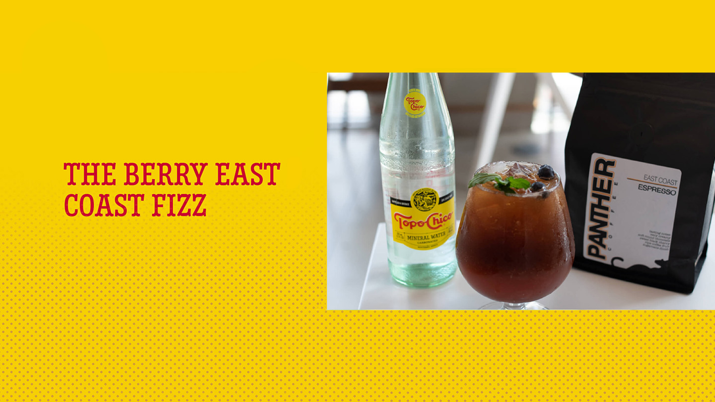 A glass of berry east coast fizz next to a Topo Chico bottle