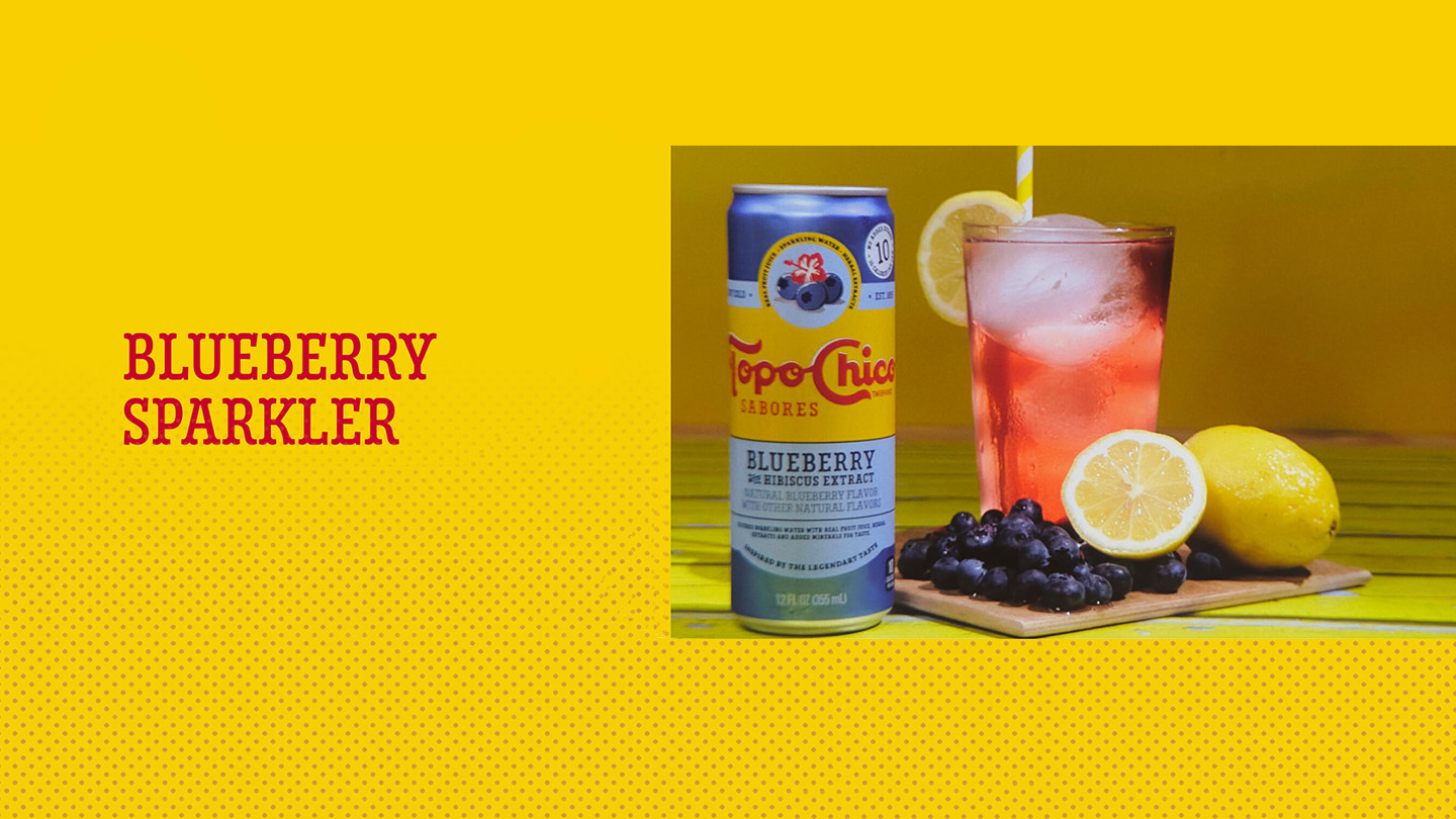 TopoChico Sabores Blueberry and a glass of Blueberry Sparkler next to some lemons and blueberries
