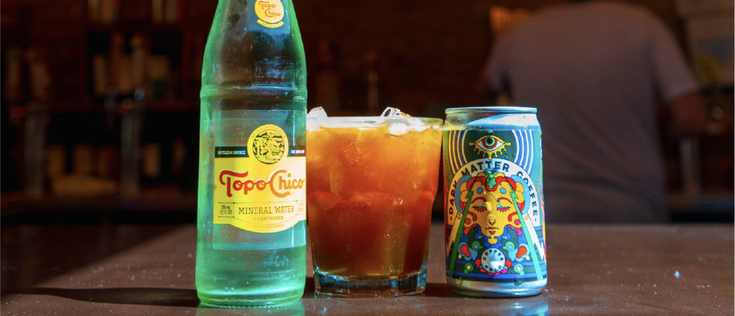 A bottle of Topo Chico next to a glass of Oh Donna drink and a can of Dark Matter Coffee