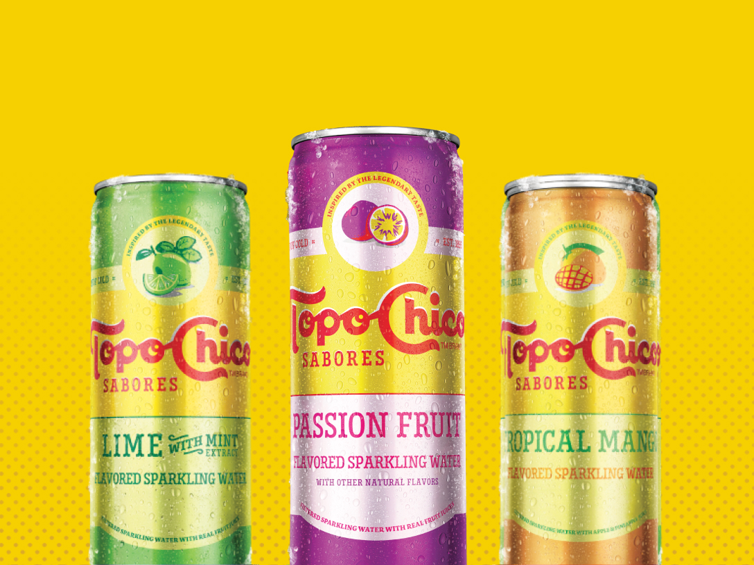 Three condensation-covered cans of Topo Chico Sabores sparkling water arranged against a yellow background: green Lime with Mint, purple Passion Fruit, and orange Tropical Mango, each labeled "Flavored Sparkling Water."