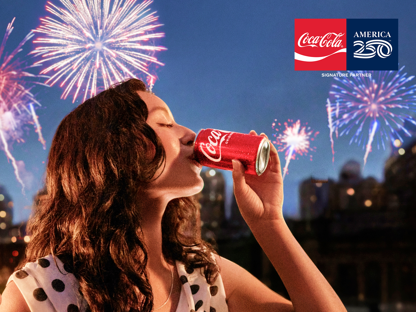 A woman drinks a Coca-Cola can while watching fireworks for the America 250 Win the Weekend promo.