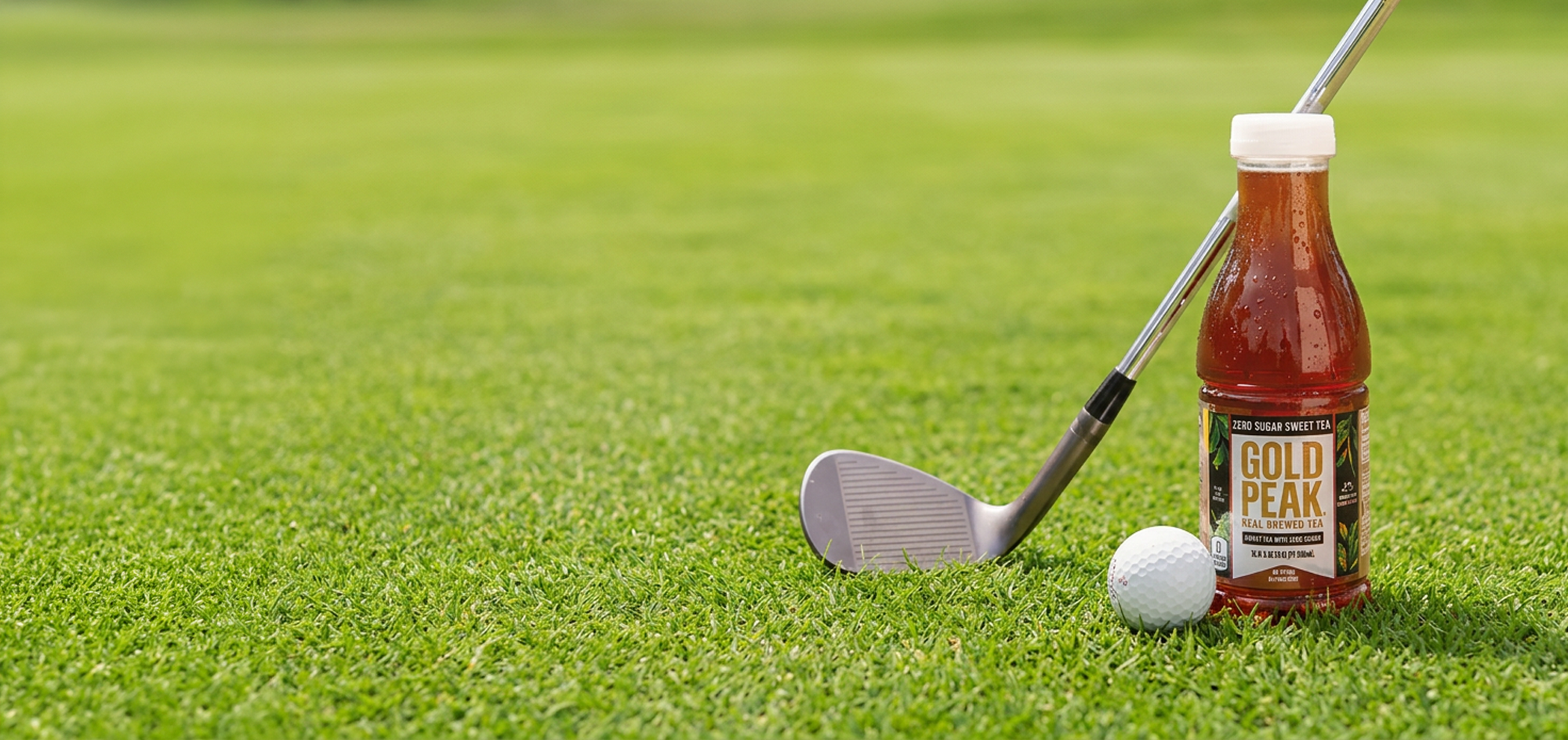 A bottle of Gold Peak Zero Sugar Sweet Tea next to a golf club and ball on a green for the PGA golf sweepstakes.