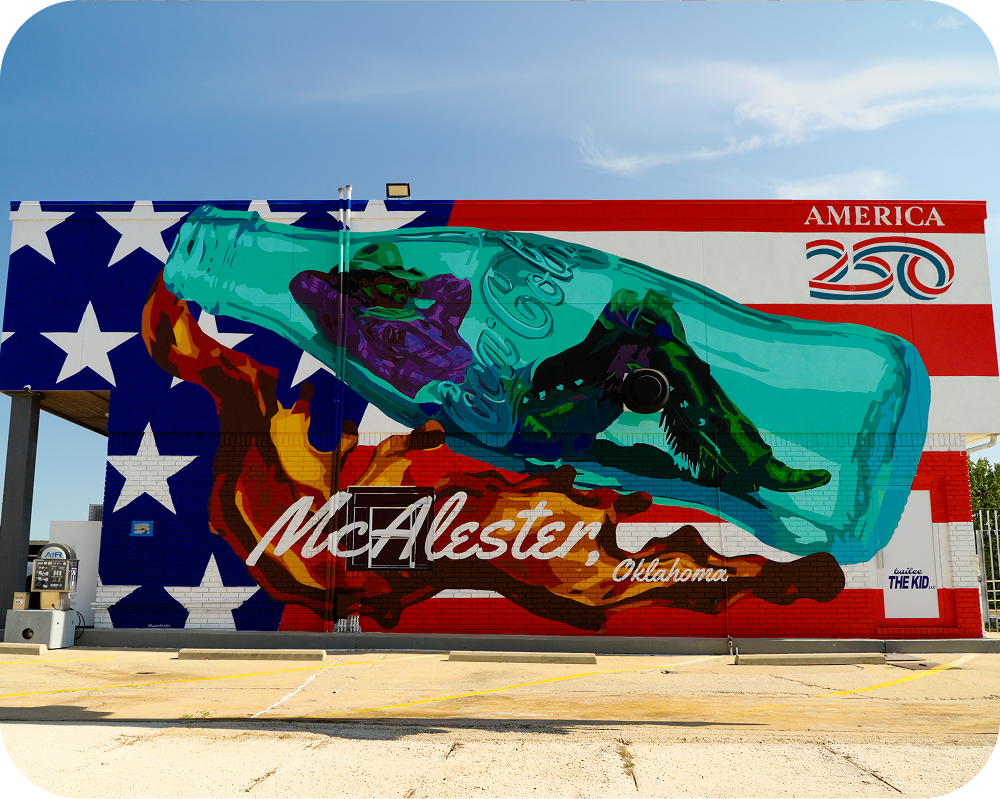 Wide shot of the completed America 250 Coca-Cola mural on a building exterior in McAlester, Oklahoma.