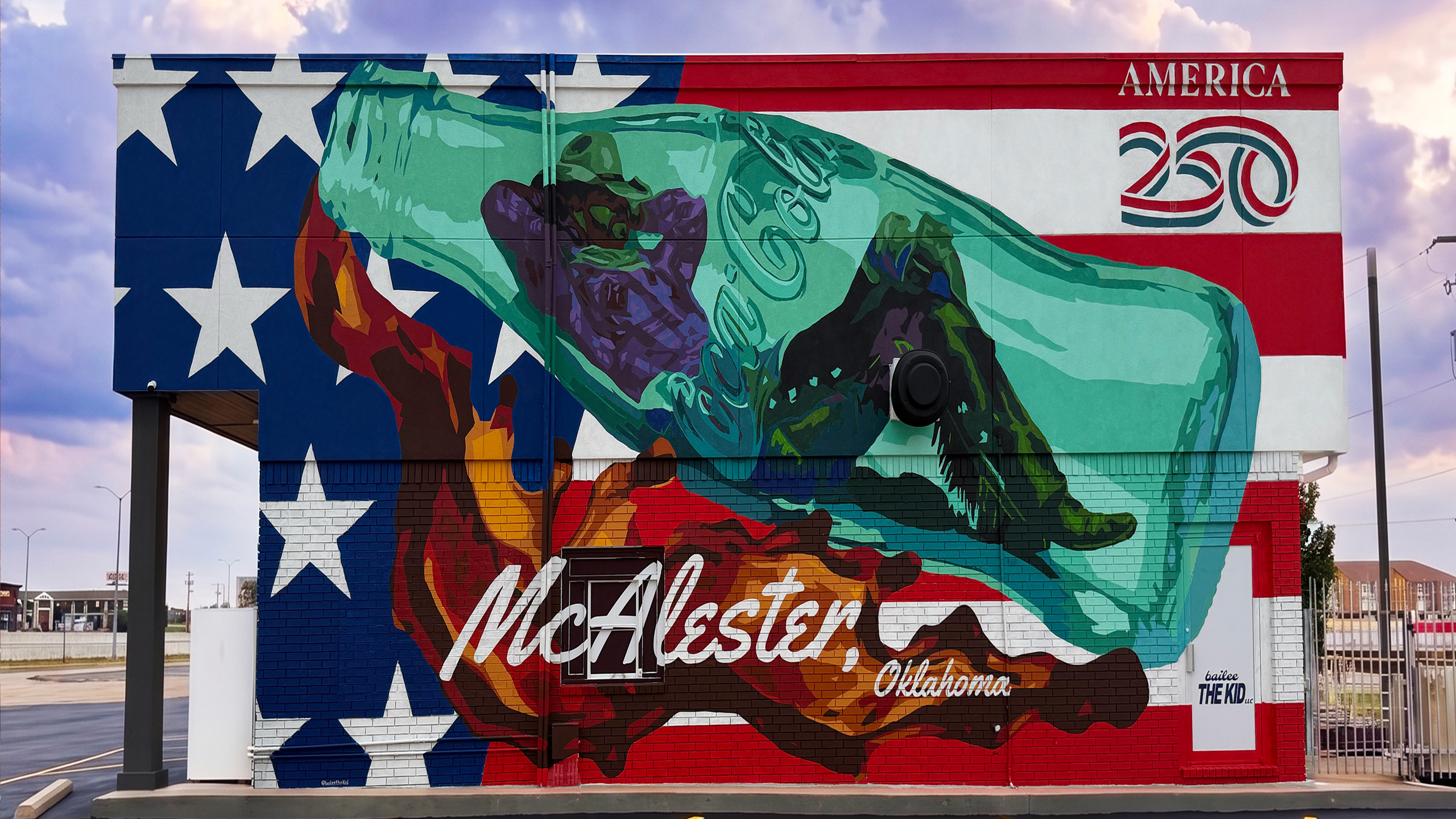 An America 250 mural in McAlester, Oklahoma, featuring a giant Coca-Cola bottle and cowboy over an American flag.