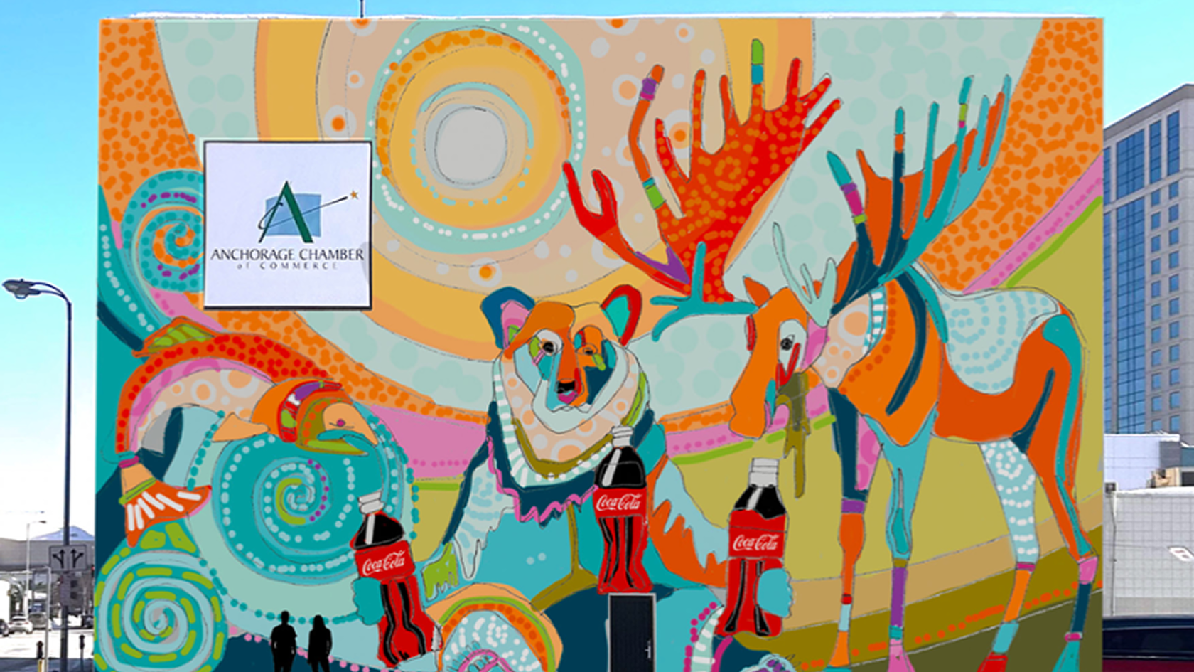 Colorful Anchorage building mural with stylized bear and moose holding Coca‑Cola bottles amid swirling patterns and sun.