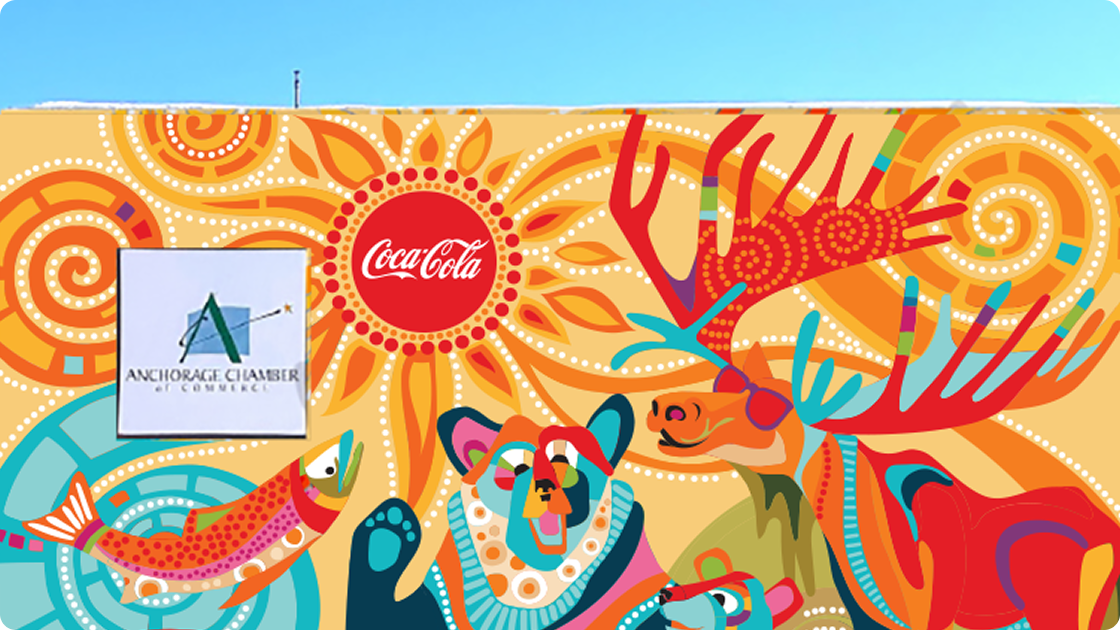 Close-up of a colorful mural with the Coca-Cola logo above the Anchorage Chamber of Commerce sign.
