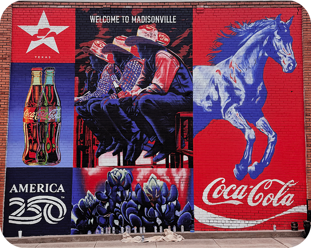 Gabriel Portillo's finished Coca‑Cola mural in Madisonville featuring cowboys, a horse, and bluebonnets.