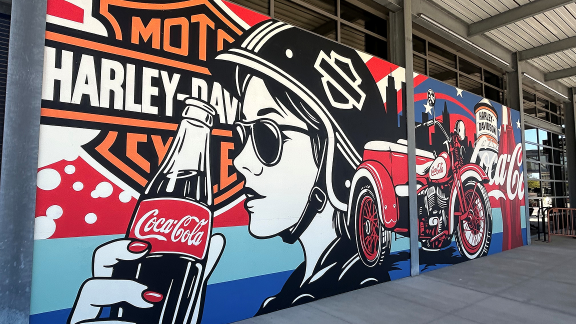Outdoor installation of the Paint the Nation Coca-Cola and Harley-Davidson mural, with bottle and motorcycle art on a building facade