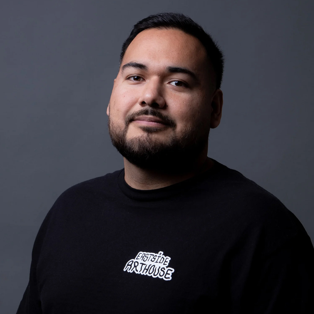 Portrait of artist Juan Navarro wearing an Eastside Arthouse shirt for the Coca‑Cola Paint the Nation campaign.