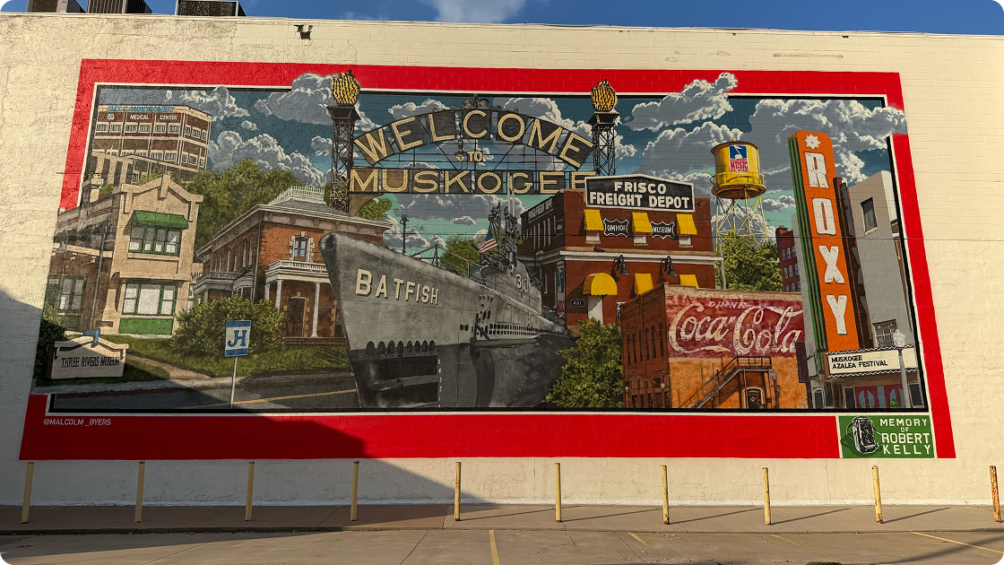 Welcome to Muskogee America 250 mural by Malcolm Byers featuring the USS Batfish and a vintage Coca-Cola ghost sign.