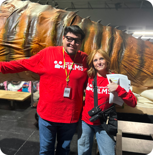 Cinemark Refreshing Films crew posing by giant dinosaur prop on set