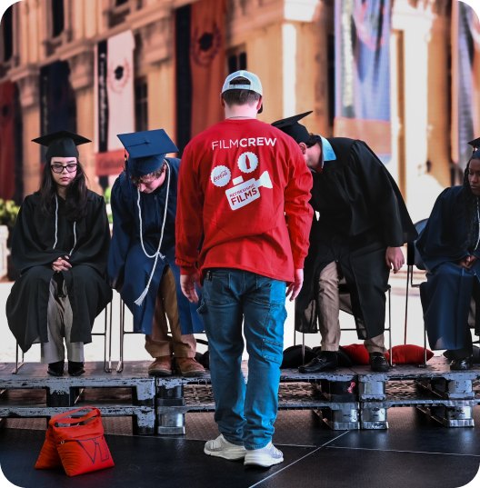 Refreshing Films crew member directing graduates on stage for Cinemark shoot