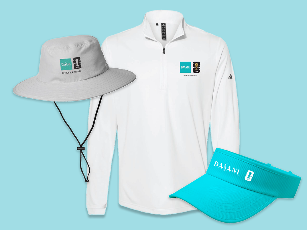 Sun‑safe DASANI FIFA swag set featuring wide‑brim hat, white quarter‑zip pullover and teal visor laid out on light blue background.
