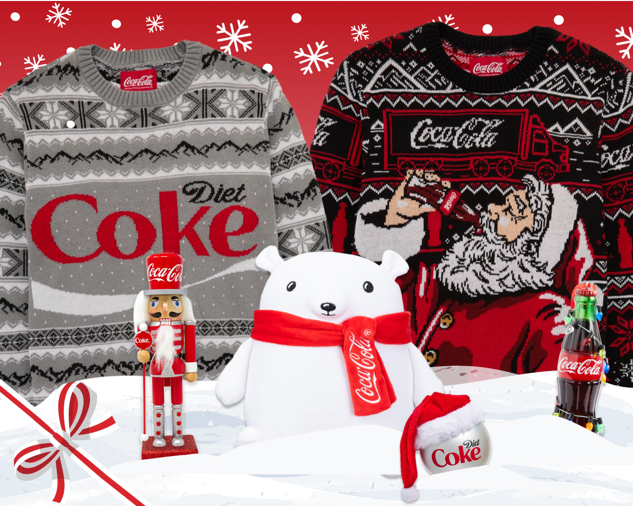 A gray knit sweater with a Diet Coke logo and a black-and-red knit sweater showing Santa drinking a Coca-Cola under a Coca-Cola truck, both against a red background with white snowflakes. In front of them, in white snow, are a red Coca-Cola nutcracker, a white polar bear plush in a red Coca-Cola scarf, a Diet Coke ornament with a Santa hat and a Coca-Cola bottle ornament wrapped in string lights.