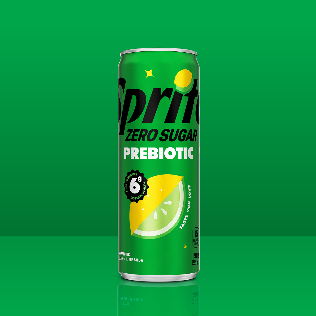 A green 12 fl oz can of Sprite Zero Sugar Prebiotic stands on a green background, decorated with a lemon and lime slice graphic. It has a badge reading “6g fiber to support digestive health,” the words “Taste you love,” and a “15 calories per can” callout.