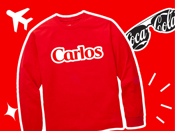 Una camiseta color rojo encendido para el aeropuerto con el nombre Carlos impreso, sobre un fondo rojo encendido. A un lado, un sticker que dice Disfruta.