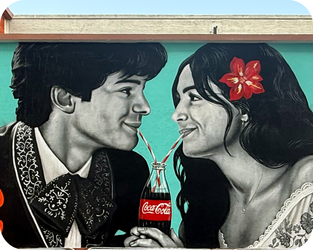 Mural de Coca‑Cola por Los Otros mostrando una pareja compartiendo una Coca‑Cola con dos popotes para Paint the Nation.