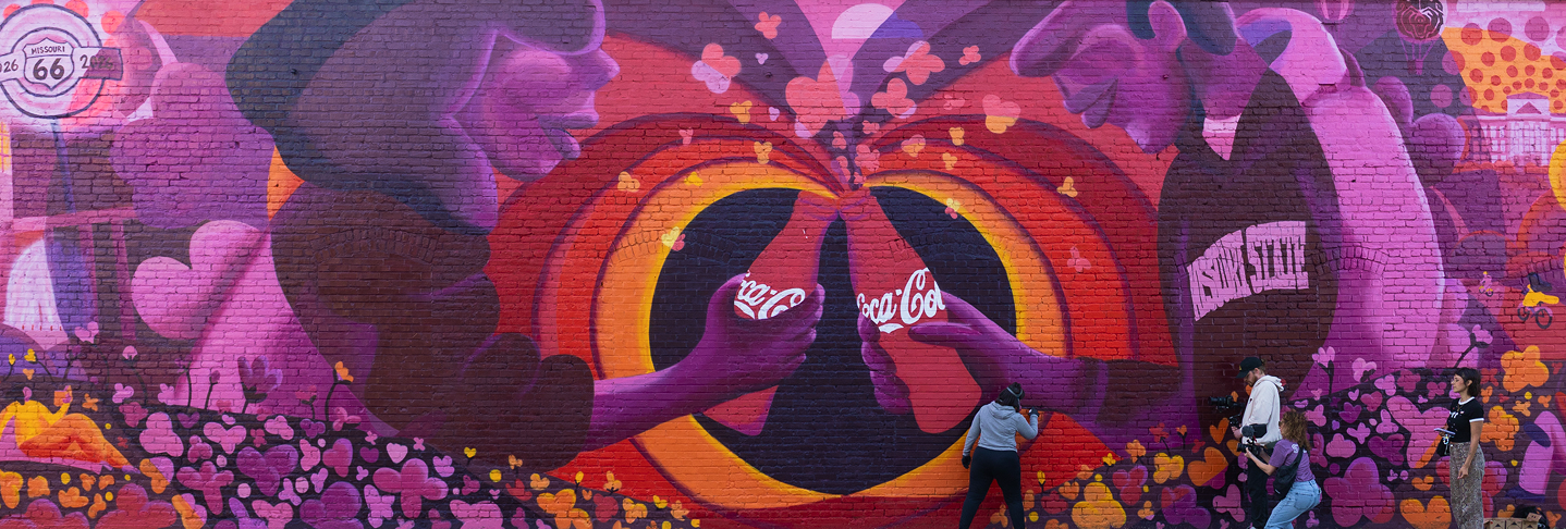 Mural Paint the Nation de Coca-Cola con botellas chocando, corazones y fans fotografiando el arte urbano