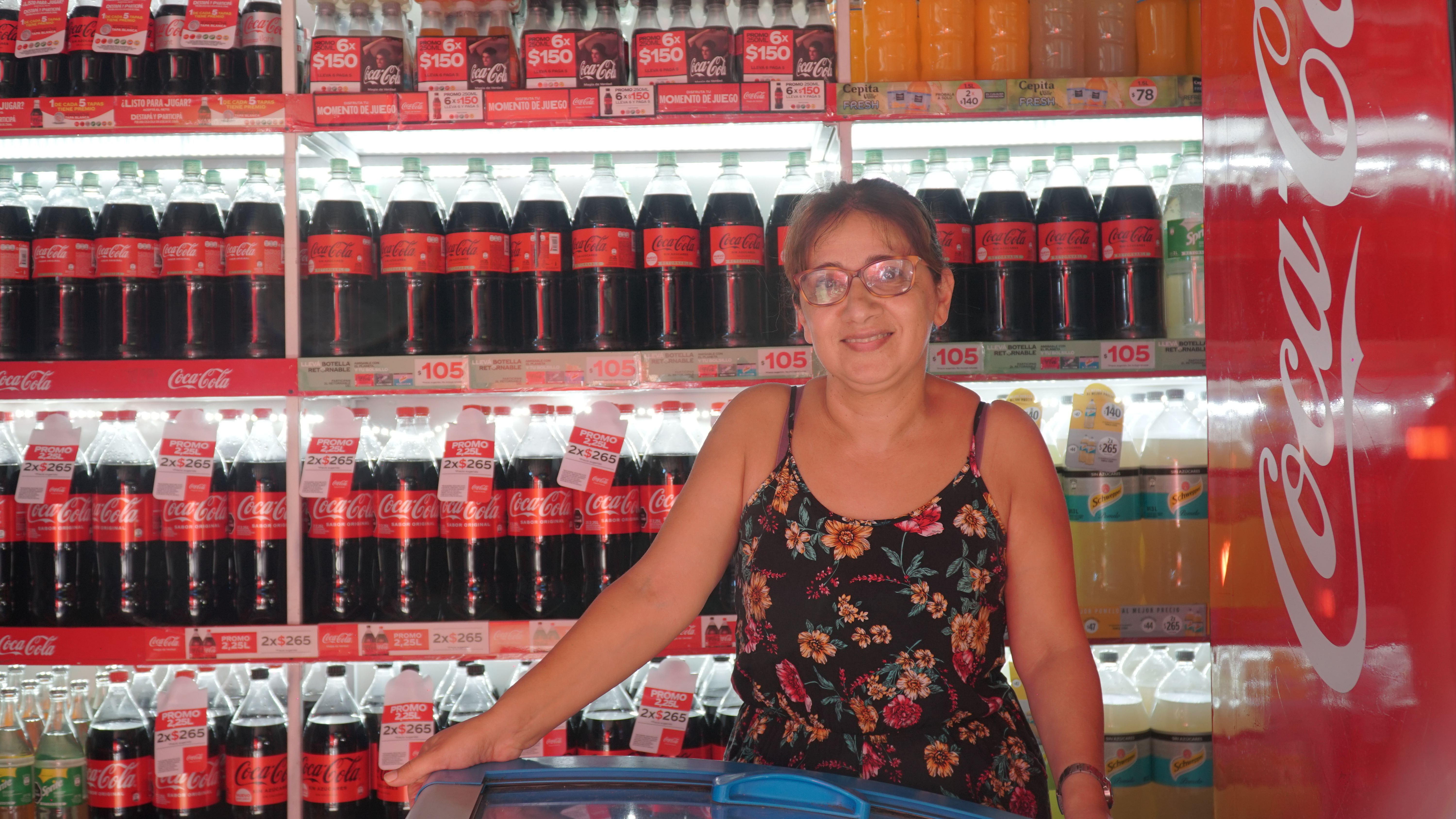 Mujer en comercio con botellas de Coca-Cola de fondo