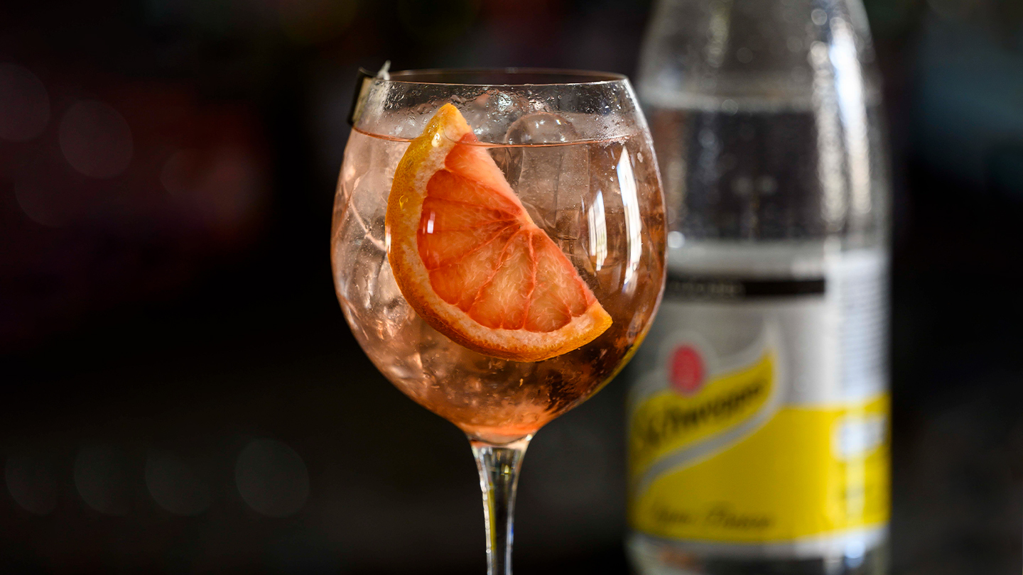 Copa de cóctel junto a botella de Schweppes