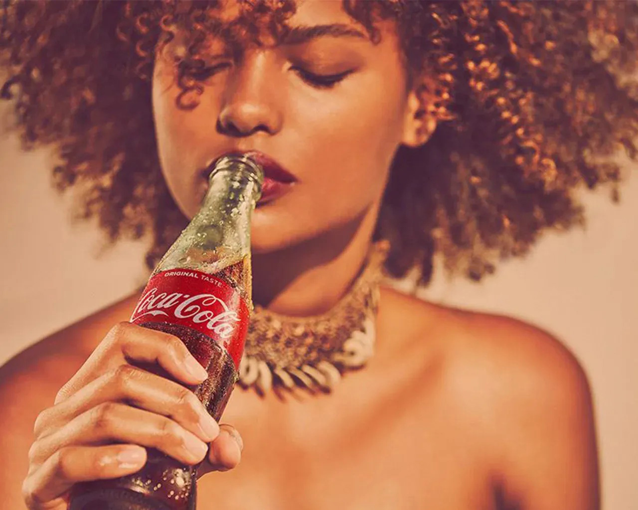 Mulher bebendo garrafa de Coca-Cola de olhos fechados