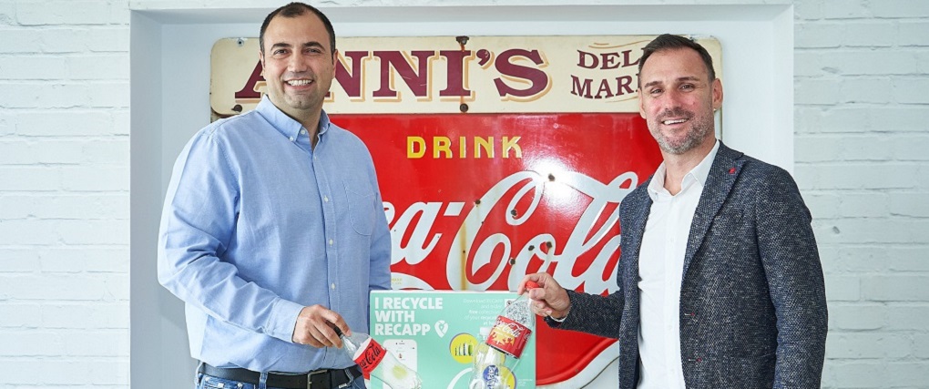 Two men with a plastic Coca-Cola bottle encourage people to recycle.