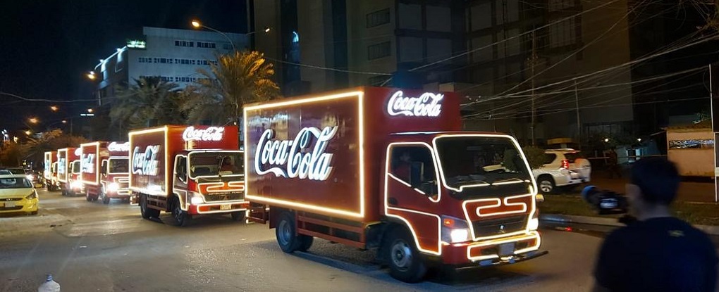 Several Coca-Cola trucks lined up on the streets