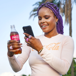 Woman taking a picture of a Coca-Cola bottle