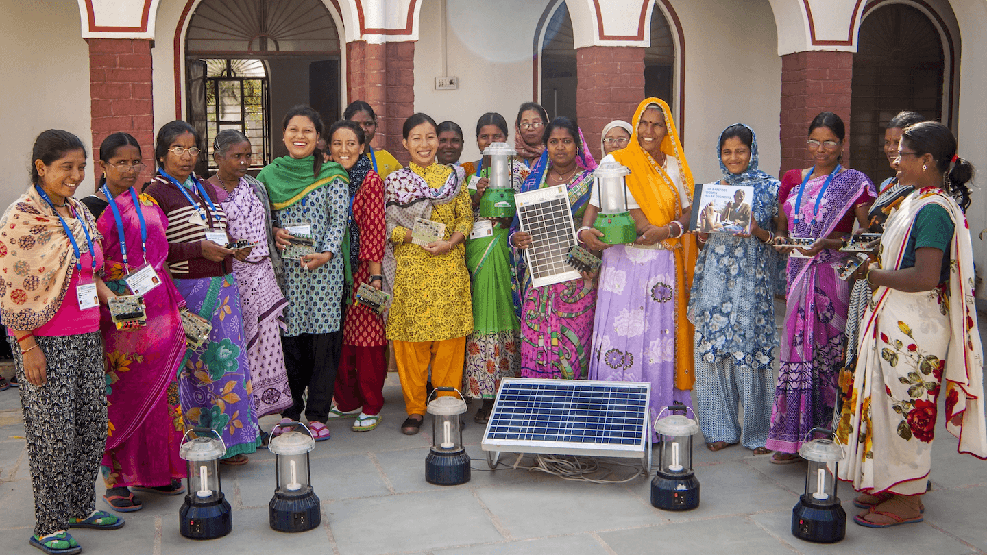 Група жена која приказује панеле соларних ћелија, мала кола и електричне лампе.